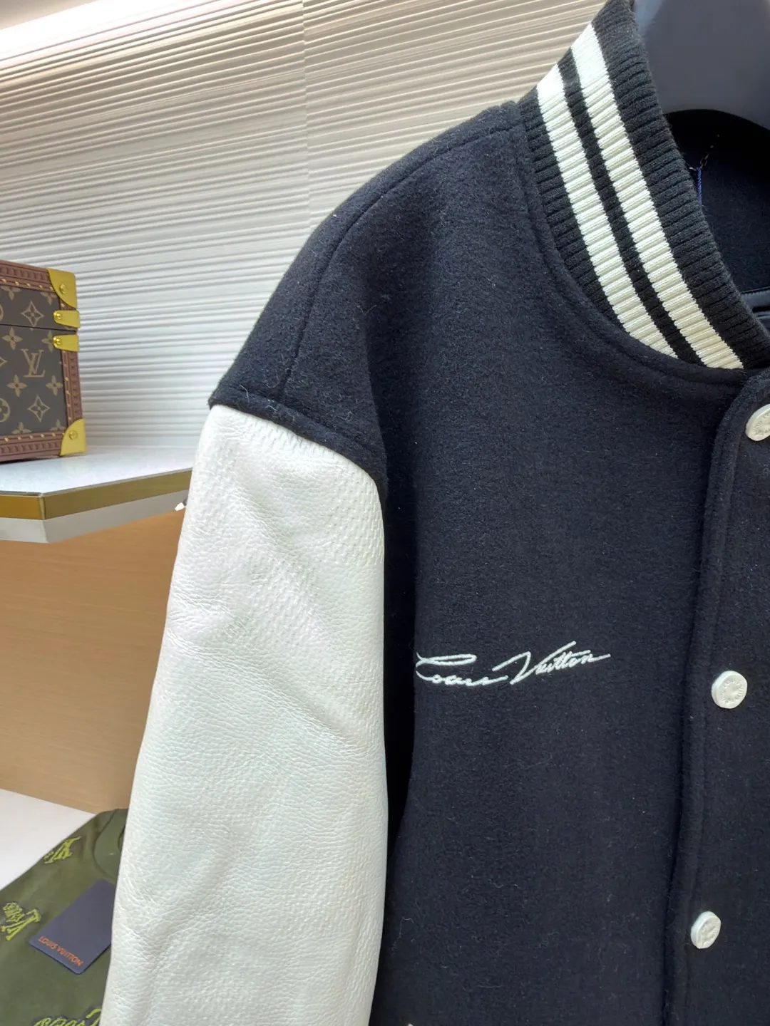 LOUIS VUITTON checkerboard embossed genuine leather and wool baseball jersey ●Original version: 51000 purchased and developed ●Item number: 1680926-i15 ●Fabric: genuine leather wool fabric ●Technology: embroidery ●Version: fitted version ●Weight: about 1770 grams ●Size: 44-46-48-50 ●Description: The fabric is made of 80% wool, with a weight of 750g. It is made of newly sheared wool and is dyed in reactive black in the vat. The colored cloth is bristle process. After brushing 5 times and washing 6 times, the fluffy surface fluff is trimmed flat, and the surface of the fabric appears fluffy. It has a hollow three-dimensional fluffy effect. You can feel the elasticity of the fabric when you touch and press it with your hands. The newly sheared wool yarn is long-fiber and is not easy to pill after shearing. The front and back panels are embroidered with Tajima embroidery machines imported from Japan. The nylon material is super matte and the tatami stitch method is multi-layered. Overlapping thread embroidery, the front chapter is made of viscose yarn, three-dimensional toothbrush embroidery, the mold is opened to determine the pile height and the suede is smoothed by hand, using acrylic round bubble beads, the surface of the bubble beads is sprayed three times, the base paint is latex paint, and the middle layer is sprayed with pearls Pearl white paint, the outer layer is sprayed with translucent glossy paint, the translucent bright white effect is completely comparable to that of mother-of-pearl. There are a total of 154 beads in the chapter. Each bead is dusted and positioned to ensure that it is flush with the edge of the chapter. The visual effect is not obtrusive. The two sleeves are made of water Made of dyed cowhide. Compared with spray-painted cowhide, there is nothing attached to the surface of water-dyed cowhide. Pure water-based dyes are continuously stirred in the tank to naturally color. During the period, samples are taken to compare the color of the Y-version sleeves according to the degree of coloring. When the colors are basically the same, they can be washed and dried naturally to produce the finished product. The thickness of the finished leather is 12mm. The embossing is made of a large-size aviation aluminum plate material mold. All the flowers are pressed according to the code positioning. An electric hydraulic control system is used, and the constant temperature and timing are automatically operated. The small sleeve logo is embossed separately from the small mold. It is pressed by electromagnetic pulse pressure and heating. After the sleeves are cut and embossed, the leather base is all shoveled to a thickness of 8mm. The leather thickness is reduced and the hand feels softer and closer to the body. The diamond-shaped plaid embossing on the surface causes an anti-skin phenomenon due to the thinning of the leather base. The pattern will naturally increase from the deep base state. Lightened, the diamond check pattern and the leather pebbles form a visually invisible effect. It is matched with cupro + cotton blended lining, the ribs are made of combed cotton yarn, and the horizontal loom imported from Taiwan has inter-color jacquard. It is matched with a custom-made molded aluminum alloy material with a logo spray-painted four-button buckle.
